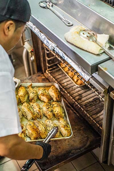 A chef putting a rack of chicken in the oven at Mulberry & Vine.