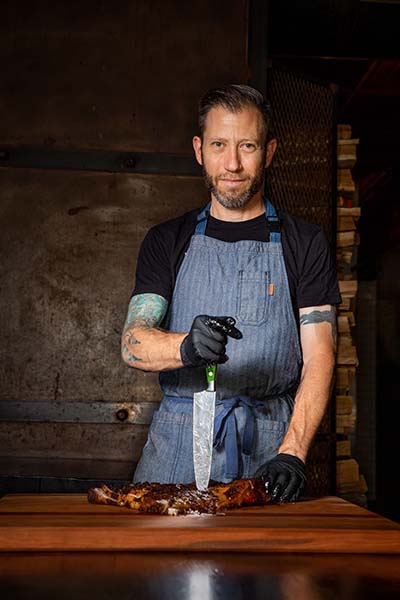 Pitmaster Hugh Mangum posing for a portrait like a knight of the roundtable